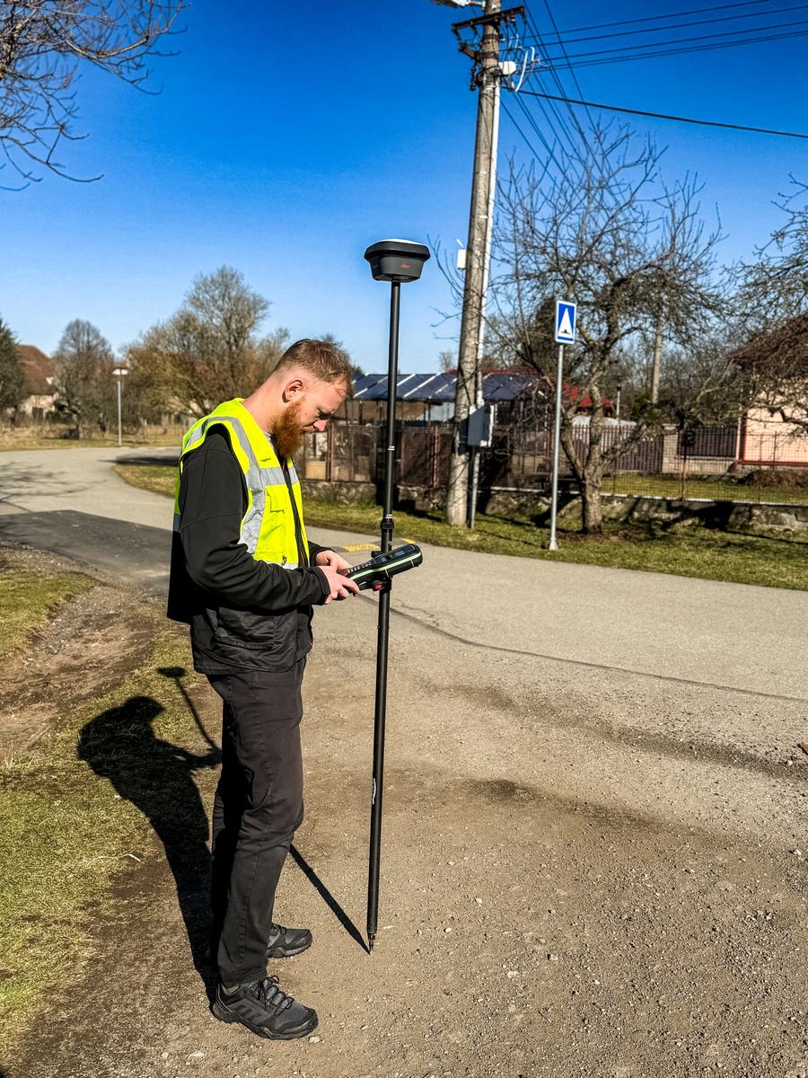 Geodet INGsite měří v obci GNSS přijímačem Leica GS05 na výtyčce, v ruce kontroler Leica CS20